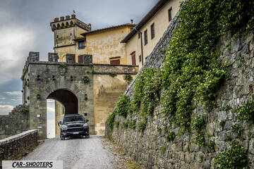Porsche Cayenne Platinum Edition – front three-quarter, black leaving a stone castle gate