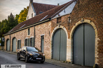Toyota C HR – front three-quarter, black against a rustic brick building