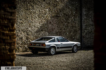 Lancia Beta Montecarlo – rear three-quarter, silver against a stone wall