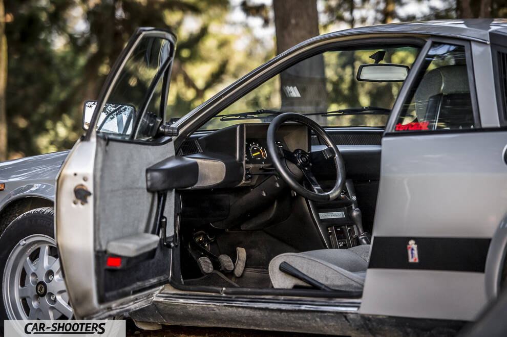Lancia Beta Montecarlo – side profile, silver with open door against trees