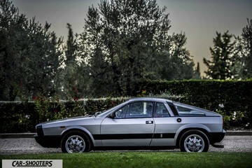 Lancia Beta Montecarlo – side profile, silver parked near a hedge and trees
