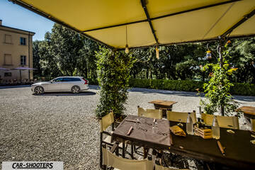 Volvo V90 T8 – side profile, silver parked near an outdoor restaurant