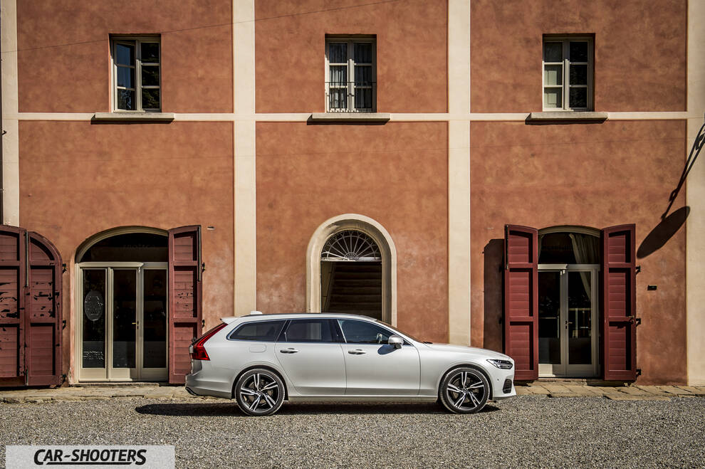 Volvo V90 T8 – side profile, white against a rustic building