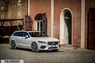 Volvo V90 T8 – front three-quarter, white parked in front of a rustic building