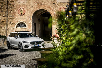 Volvo V90 T8 – front three-quarter, white against an old stone building