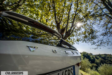Volvo V90 T8 – rear view, white parked under trees