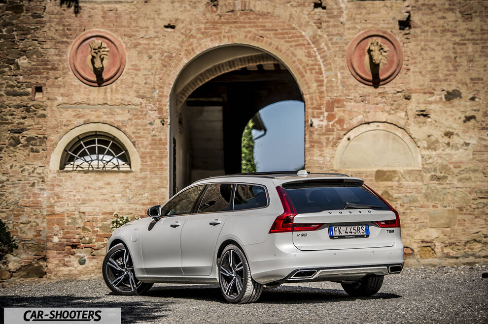 Volvo V90 T8 – rear three-quarter, silver against an old stone building