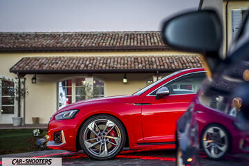 Audi – front three-quarter, red parked in front of a building