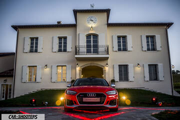 Audi – front three-quarter, red parked in front of a large building