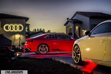 Audi – rear three-quarter, red parked in a courtyard at dusk