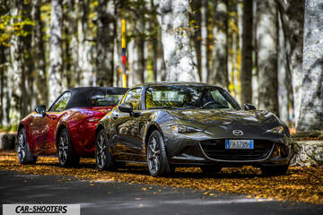 Mazda MX 5 ND – front three-quarter, grey metallic on a road in autumn woods