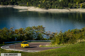 Abarth 595 Competizione – front three-quarter, yellow on a winding lakeside road