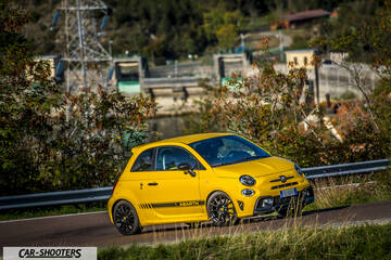 Abarth 595 Competizione – front three-quarter, yellow on a road near a dam