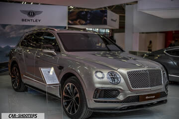 front three-quarter, silver metallic at an indoor auto show