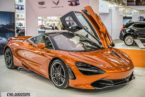 front three-quarter, orange metallic at a car show