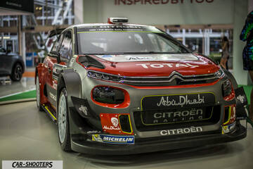 front three-quarter, grey and red on an auto show floor