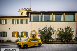 Audi Q2 – front three-quarter, yellow in front of a large building