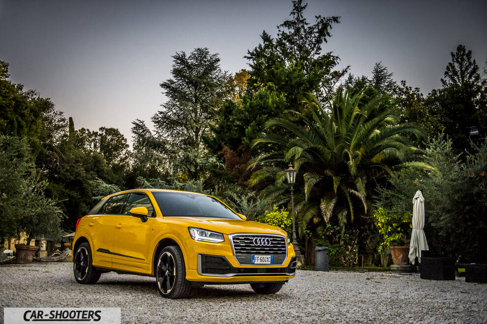 Audi Q2 – front three-quarter, yellow against a lush garden backdrop