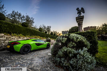 Mclaren 570S – rear three-quarter, bright green parked near an old stone statue and castle walls