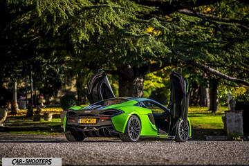Mclaren 570S – rear three-quarter, bright green with doors open in a park