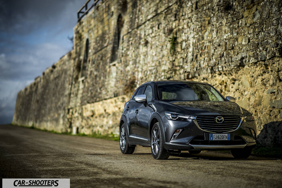 Mazda CX 3 – front three-quarter, dark grey metallic against an old stone wall