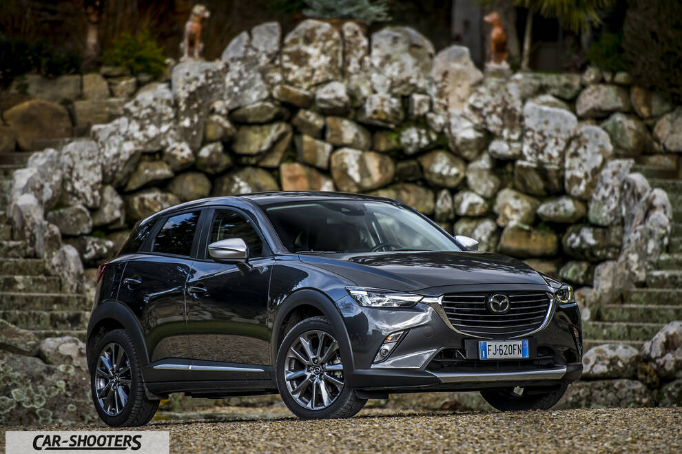 Mazda CX 3 – front three-quarter, dark grey against a stone wall backdrop