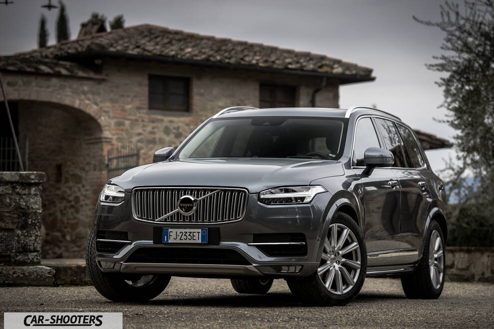 Volvo XC90 – front three-quarter, grey metallic against a rustic building