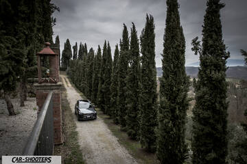 Volvo XC90 – front three-quarter, dark grey on a country path lined with trees