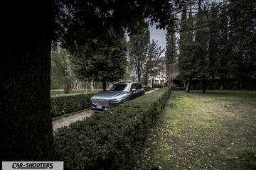 Volvo XC90 – front three-quarter, grey metallic on a driveway bordered by hedges