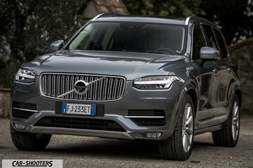 Volvo XC90 – front three-quarter, grey metallic against a stone wall backdrop