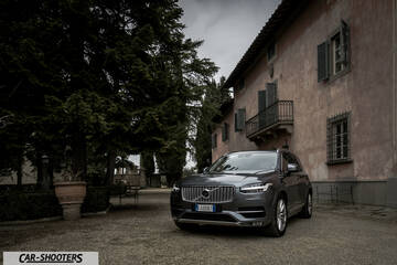 Volvo XC90 – front three-quarter, grey metallic against a rustic building