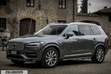 Volvo XC90 – front three-quarter, grey metallic against a rustic stone building background