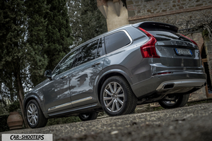 Volvo XC90 – rear three-quarter, grey metallic against a rustic building