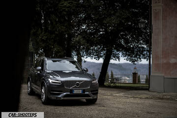 Volvo XC90 – front three-quarter, grey metallic parked near an old building