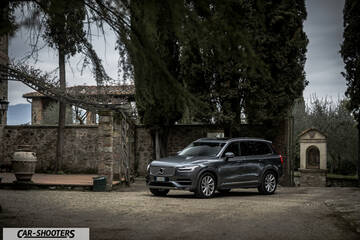 Volvo XC90 – front three-quarter, grey metallic in a rustic courtyard