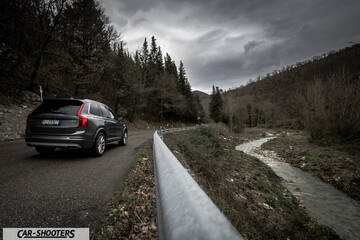 Volvo XC90 – rear three-quarter, dark grey metallic on a country road next to a stream