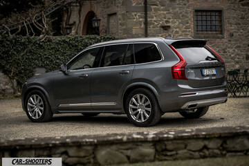 Volvo XC90 – rear three-quarter, grey metallic against a rustic stone building