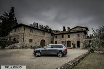 Volvo XC90 – side profile, grey metallic in front of rustic stone buildings