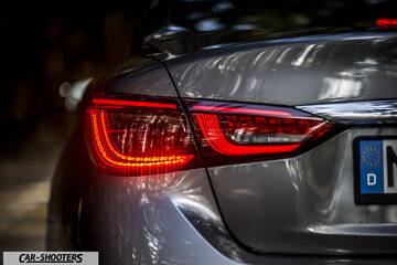 Infiniti Q50 – rear three-quarter, grey metallic with illuminated taillight