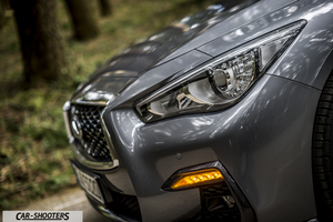 Infiniti Q50 – front three-quarter, grey metallic in a wooded area