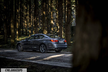 Infiniti Q50 – rear three-quarter, grey metallic on a forest road