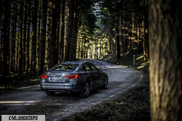 Infiniti Q50 – rear three-quarter, grey metallic on a country road
