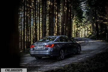 Infiniti Q50 – rear three-quarter, grey metallic on a forest road