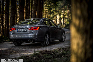 Infiniti Q50 – rear three-quarter, grey metallic on a forest road