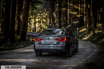 Infiniti Q50 – rear view, grey metallic on a forest road