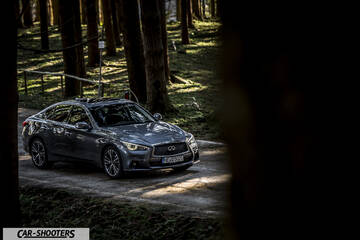 Infiniti Q50 – front three-quarter, grey metallic on a forest road