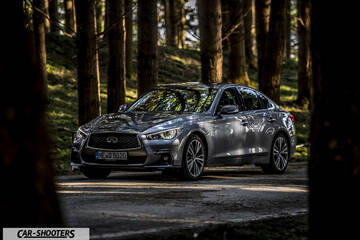 Infiniti Q50 – front three-quarter, grey metallic on a forest road