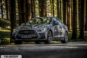 Infiniti Q50 – front three-quarter, grey metallic on a forest road