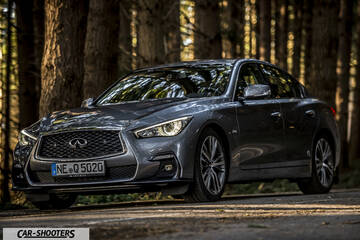 Infiniti Q50 – front three-quarter, grey metallic on a forest road