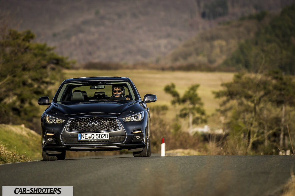 Infiniti Q50 – front three-quarter, dark grey on a country road